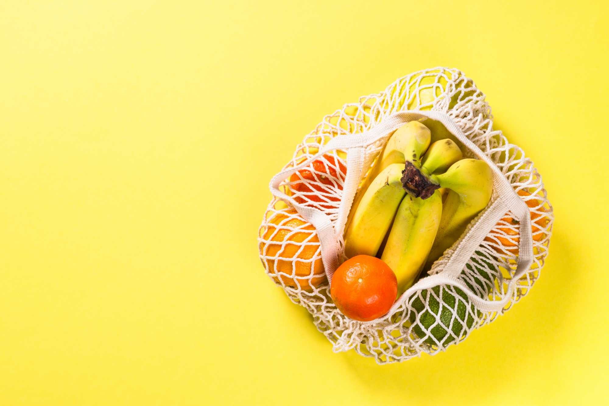 mesh-bag-with-fruits-on-color-background-R9T43M8.jpg